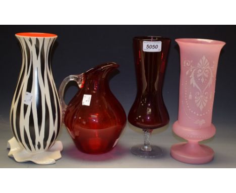 A pink glass footed cylindrical vase, enamelled white decoration; a ruby glass jug, clear glass fluted handle; a ruby glass f