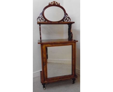 A mid Victorian walnut music cabinet, having an oval mirrored upstand with a fretwork bracket and shelf, over a mirror panell