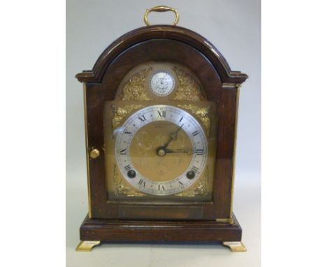 A modern Georgian style mahogany cased bracket clock, the arched top with a folding top handle, over a glazed, panelled door,