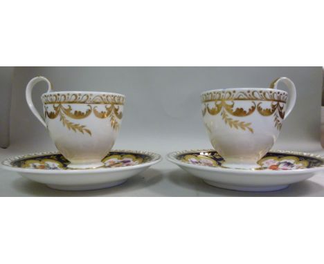 A pair of early/mid 19thC, probably Coalport, china tea cups and saucers, decorated with floral vignettes and gilding, on a m