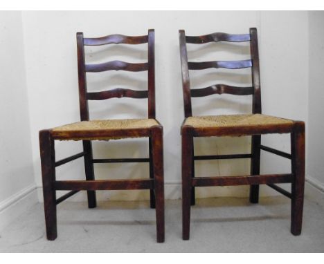A pair of mid 19thC country made, fruitwood framed ladder back side chairs, having woven rush seats, raised on square, tapere
