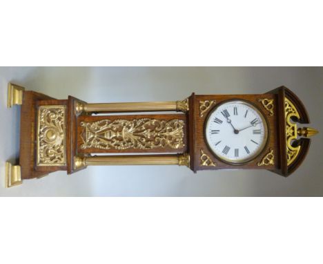 An early 20thC mantel timepiece, fashioned as a miniature light oak longcase clock with lacquered, decoratively cast brass mo