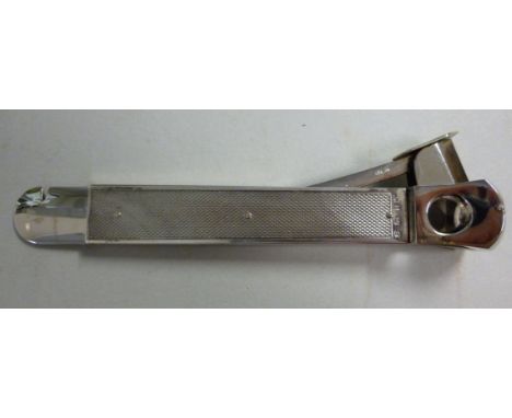 A stainless steel and silver clad cigar cutter with engine turned decoration  WM  Birmingham 1978