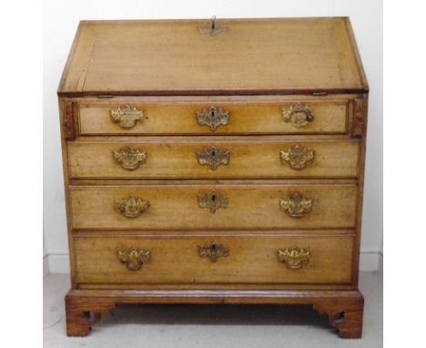 A George III oak bureau, having a mitred fall front, enclosing a green hide scriber and fitted interior, over four graduated 