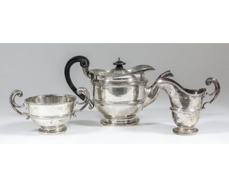 A George V silver circular three piece tea service with moulded rims and girdles and high C-scroll handles, comprising - teap