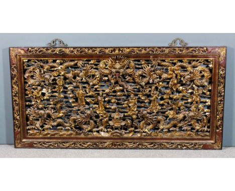 A Chinese red painted and gilt decorated hardwood rectangular panel fretted and carved with dragons, figures, pagodas, fish a