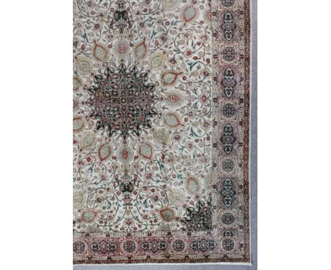 A Tabriz carpet woven in pastel colours with a bold central medallion surrounded by palmettes, with trailing floral ornament,