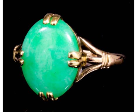 A Chinese gold coloured metal mounted green jade set ring, the oval cabochon cut stone of approximately 3ct, within claw sett