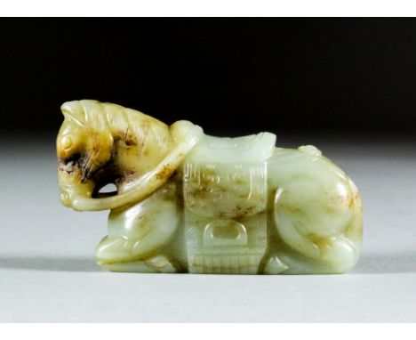 A Chinese mottled celadon jade carving of a recumbent horse with carved saddle and reins, 3.5ins (9cm) wide (late Ming Dynast