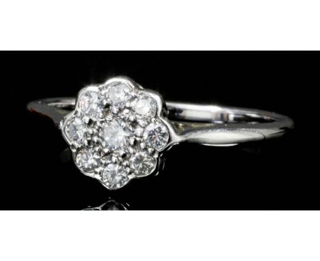 A modern 18ct white gold all diamond set flowerhead pattern ring, the face pave set with nine small brilliant cut diamonds (e