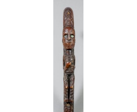 A Maori carved wood walking stick, carved with two Tiki figures, linear and swirl decoration and set with abalone, 35.5ins ov