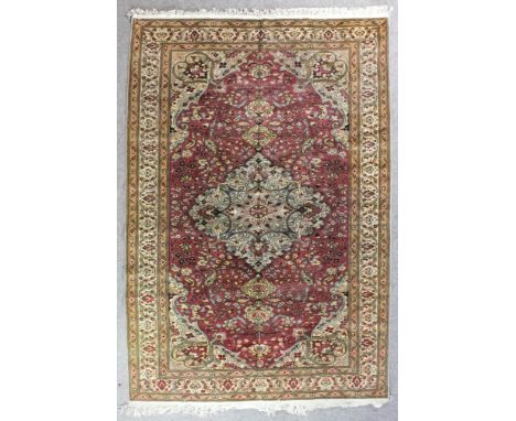 An Anatolian Kayseri carpet woven in colours with a bold central medallion filled with trailing leaf ornament and with confor