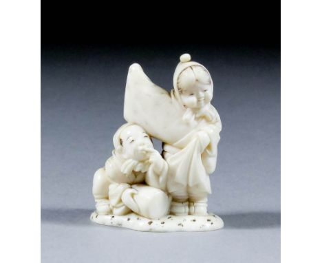 A Japanese carved ivory netsuke of two children, a standing girl wearing kimono with outstretched right arm and a crouching b