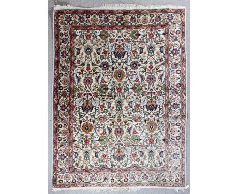 A Tabriz carpet woven in colours with bold trailing floral palmettes, on an ivory ground, within conforming three stripe bord