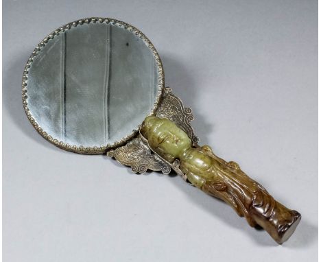 A Chinese white metal and jade handled hand mirror, the handle carved with a figure of a standing woman, the metal embossed w