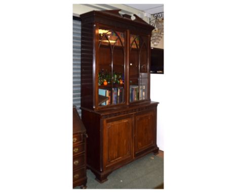 Reproduction mahogany two section bookcase having architectural pediment and dentilled cornice, the base fitted two panelled 