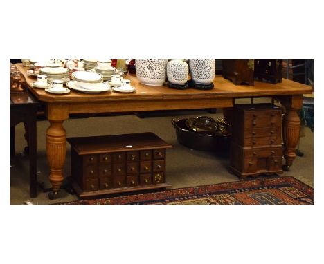 Edwardian light oak wind-out extending table with canted oblong top on reeded turned tapered supports with castors, extending