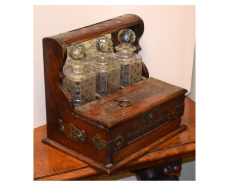 Late Victorian carved oak three bottle tantalus, with silver-plated mounts and hinged two-flap top over base drawer, 36.5cm w