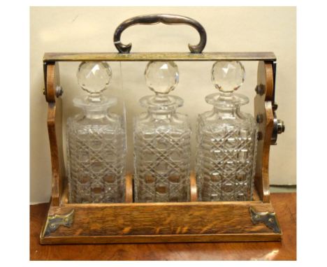 Late Victorian silver-plated oak three bottle tantalus, with dedication inscription dated 1894 to the Cardigan Lawn Tennis Cl