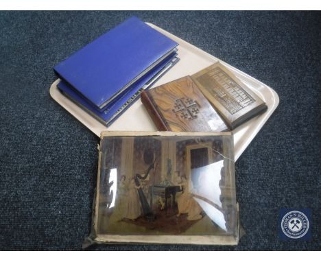 A tray containing two albums of vintage postcards, unframed chrystoleum, wooden album containing souvenir flowers from The Ho