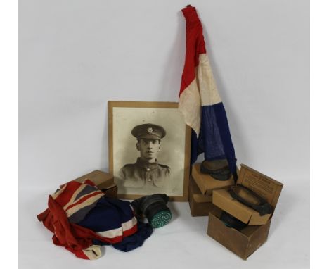 THREE VINTAGE GAS MASKS IN ORIGINAL CARD BOXES, a quantity of British and French flags and a WWI portrait photograph of a sol
