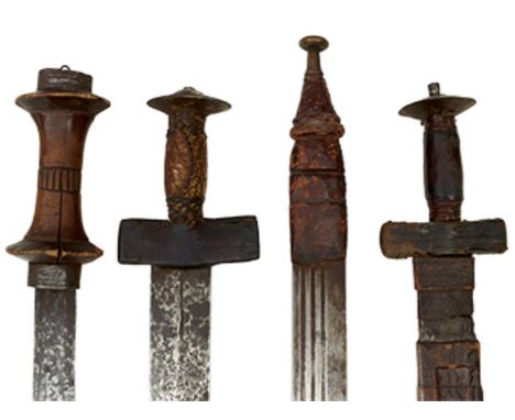 FOUR AFRICAN SWORDS, the first, Takouba, 76.5cm blade in the European style, fullered and with opposing crescent stamps, rein