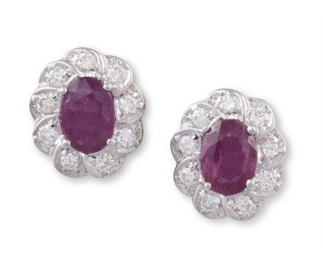 A PAIR OF RUBY AND DIAMOND EARSTUDSEach oval-shaped ruby, within a four-claw setting, in a surround of round brilliant-cut di