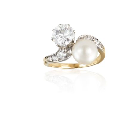 A DIAMOND AND PEARL CROSS-OVER RING, CIRCA 1910Obliquely-set with a transitional brilliant-cut diamond weighing approximately