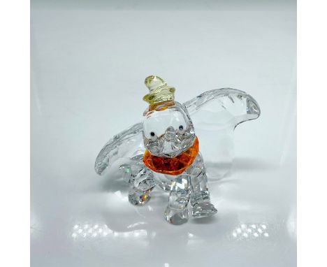 Brilliant clear faceted crystal figure of the classic elephant seated wearing a bright orange collar and pale yellow hat. Cre