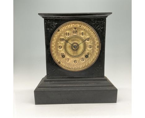 Block form exterior enameled metal case with ornate impressed marks around clock face. Clock face is round gilt incised desig