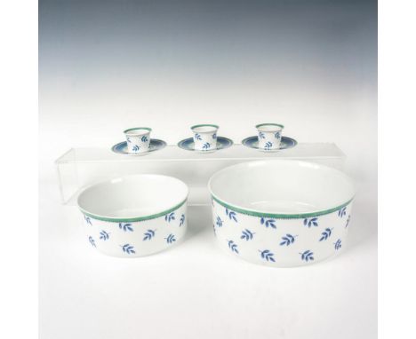 A set of 2 porcelain serving bowls of different sizes and 3 porcelain egg cups that all share the same design of blue leaves 