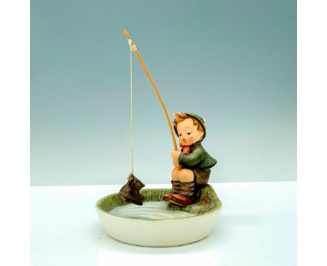 A figure of a young boy in a green jacket and hat fishing on a lakeside with a boot he pulled from his rod. Goebel Hummel bac