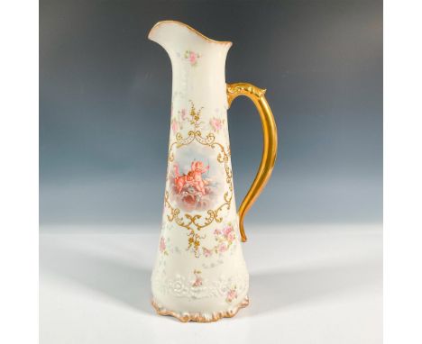 A white and gilded tall pink floral pitcher. Beautifully adorned with two cherubs, and one is holding a bow and arrow. Emboss