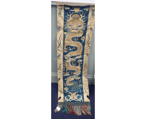 A CHINESE EMBROIDERED WALL HANGING depicting a dragon chasing a flaming pearl, circa late 19th century 40 x 135cm (damaged)