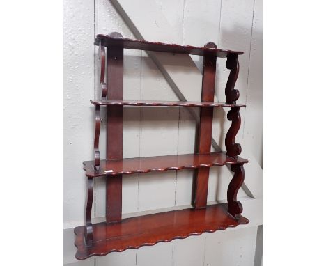 A VICTORIAN MAHOGANY WALL HANGING SHELF four graduated shelves with 'S' scroll supports 64cm wide