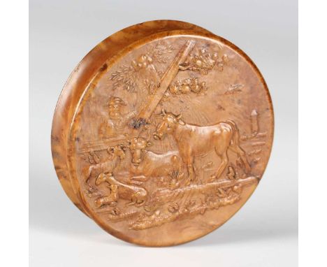 An early 19th century pressed maple circular snuff box, the lid decorated in relief with a farmer and cattle, the interior li
