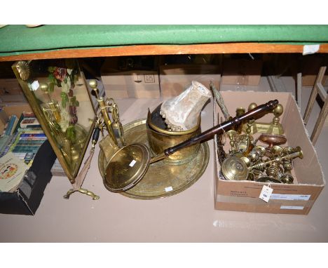 A quantity of brassware, to include: a copper and brass powder flask; two pairs of early 20th Century candlesticks; a firedog