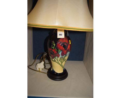 A modern Moorcroft table lamp, decorated with poppies on dark blue and cream ground, complete with cream coloured shade.