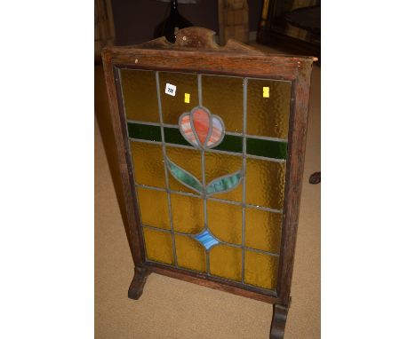 A stained wood firescreen with stained glass panel.