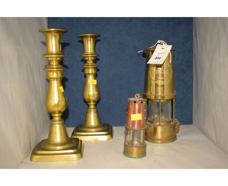 A reproduction miner's lamp, by The Protector Lamp and Lighting Company; two brass candlesticks; and a miniature reproduction