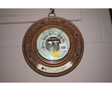 An aneroid barometer in circular carved and stained wood mount, fitted a thermometer.