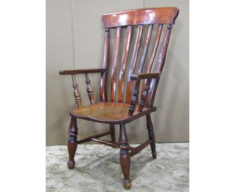 A Windsor stained lathe back armchair with saddle shaped seat raised on turned supports and stretchers 