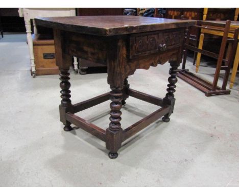 An antique walnut side table with rectangular top over a carved frieze drawer with shaped apron raised on turned bobbin and b