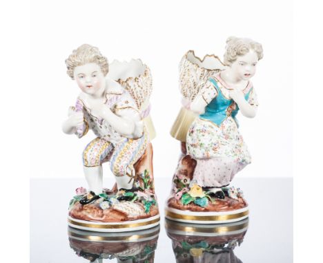 TWO MEISSEN FIGURES
modelled as a boy and a girl each holding a basket and resting on top of a tree trunk, each with a natura