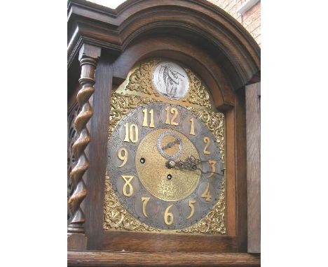 An Edwardian oak cased chiming longcase clock, the case having full length barley twist columns, decorative carving and slide
