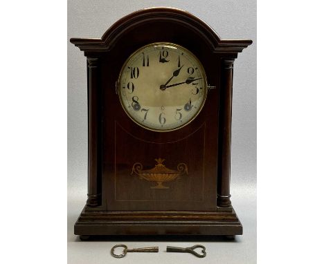 EDWARDIAN MAHOGANY ARCHED MANTEL CLOCK - inlaid with stringing and central urn motif, with turned pillars flanking the circul