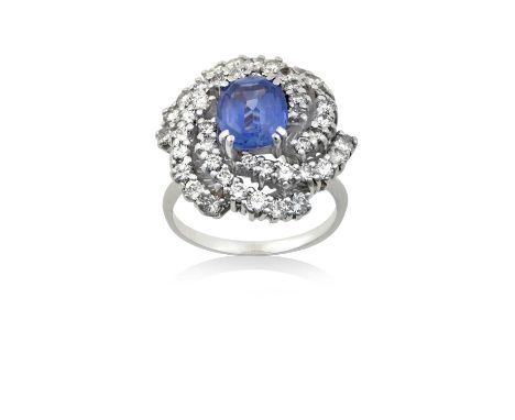 A Sapphire and Diamond Cluster Ringthe cushion cut sapphire within a radiating border of round brilliant cut diamonds, in whi