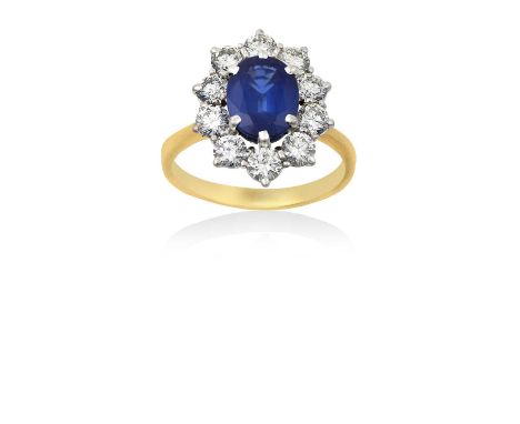 An 18 Carat Gold Sapphire and Diamond Cluster Ringthe oval cut sapphire within a border of round brilliant cut diamonds, in w