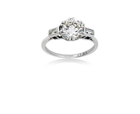 A Diamond Solitaire Ringthe old cut diamond in a white double claw setting, to baguette cut diamond set shoulders, on a plain