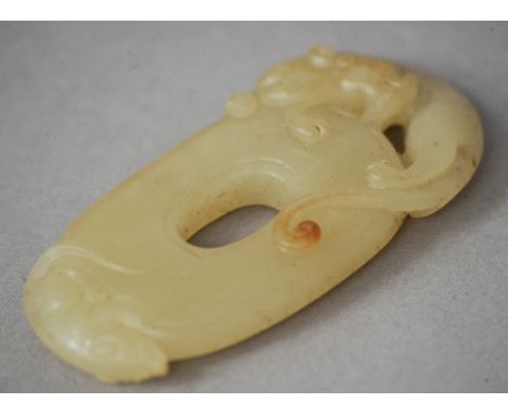 A Chinese carved jade bi disk
Surmounted with the figure of a dragon.  6 cms long. CONDITION REPORTS: Generally in good condi